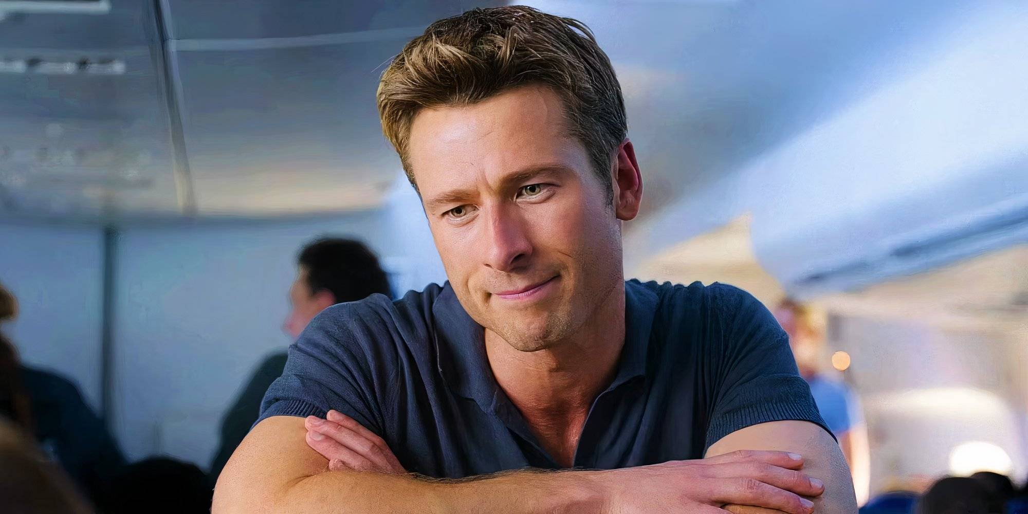 close up of glen powell leaning over an airplane seat and facing the camera in anyone but you