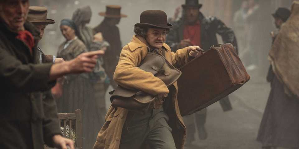 jack gleeson as byron hedges running through the street with his luggage in house of guinness