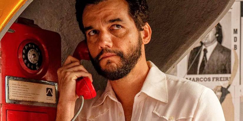wagner moura on the phone at a phone booth in the secret agent